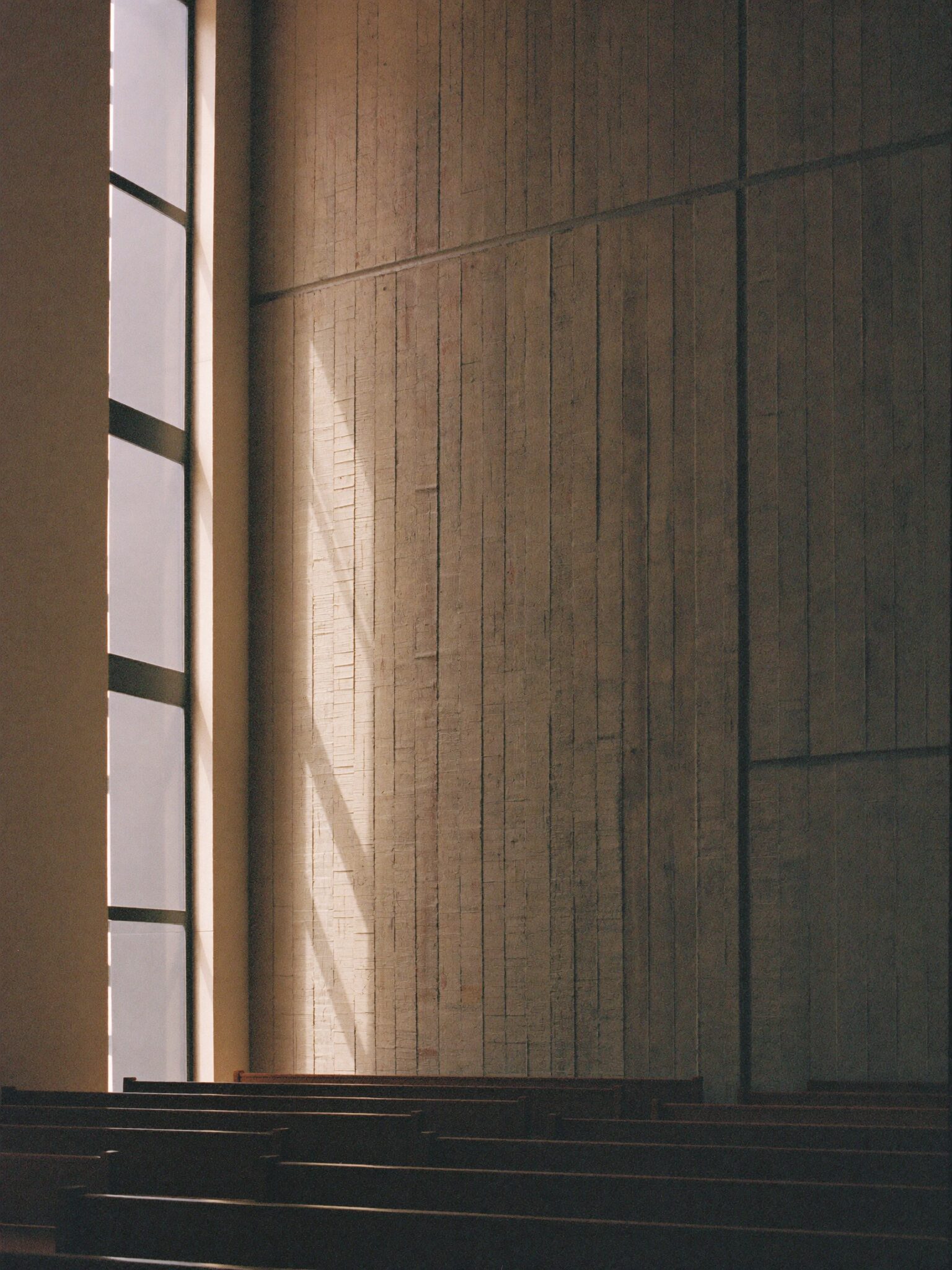 Concrete chapel interior with a vertical shaft of warm light