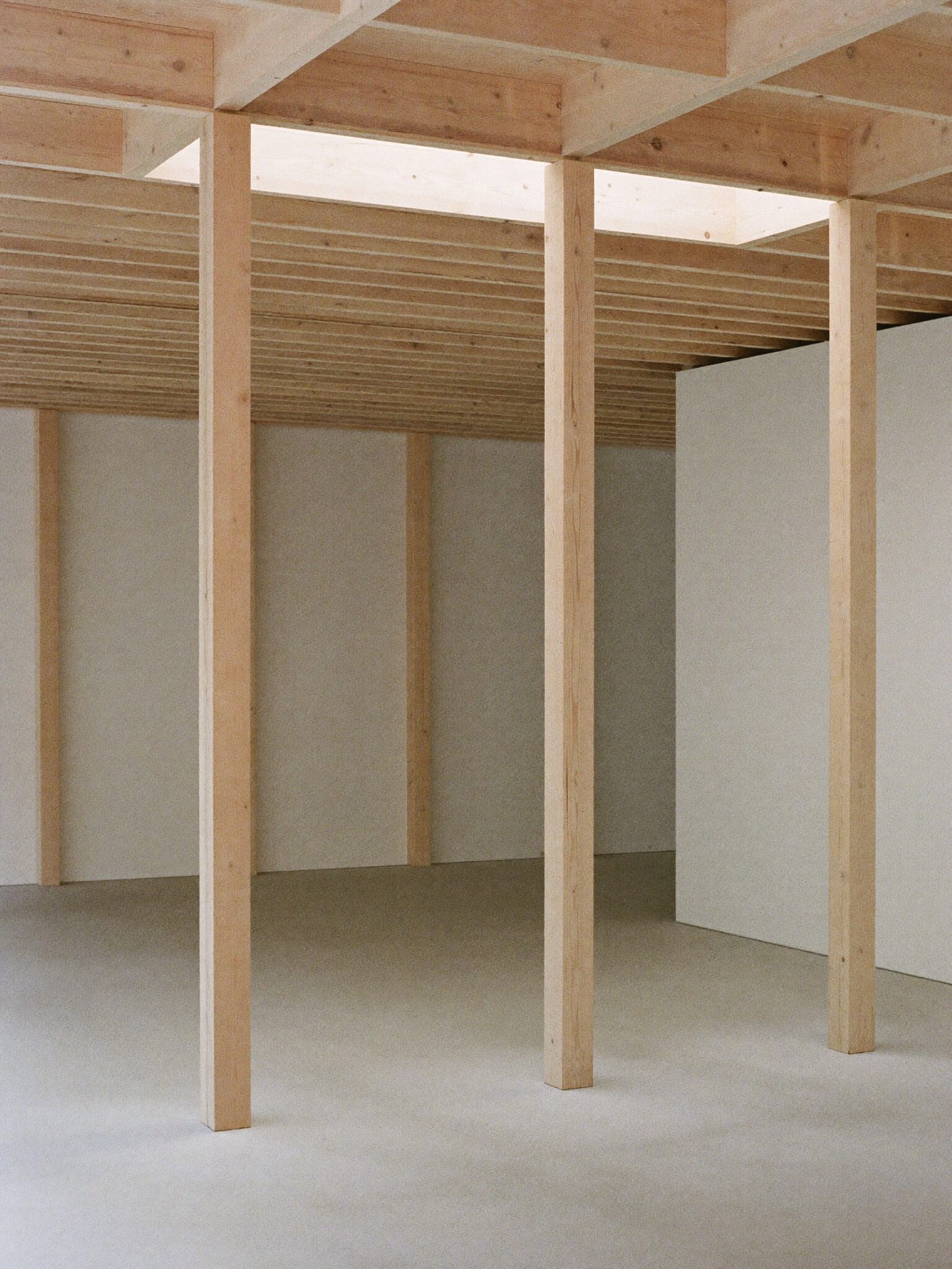 Pale timber pavilion interior with rhythmic columns and skylight