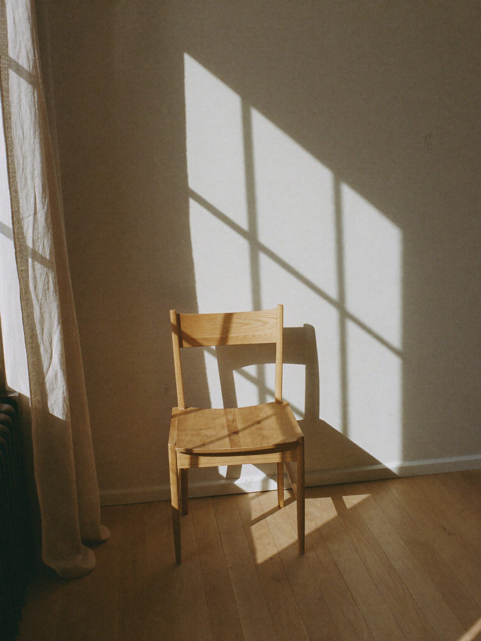 Oak chair beside a window, shadow pattern on plaster