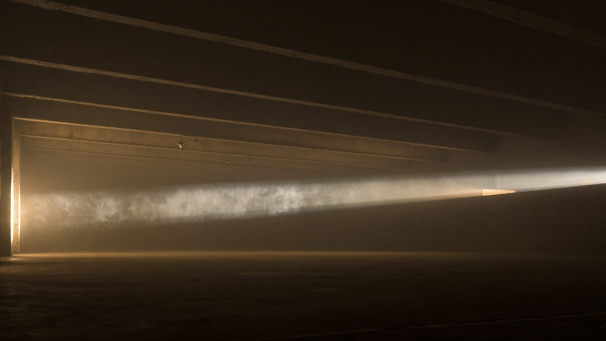 A blade of light crossing a vast dark hall